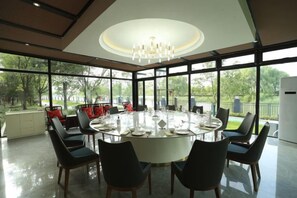 Un comedor amplio con una mesa redonda dispuesta para seis personas, rodeada de sillas, ventanas grandes y vistas al exterior.