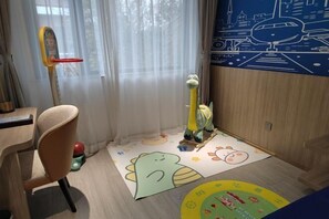 Un espace de jeux pour enfants avec un panier de basket, une girafe en jouet et un tapis de jeu coloré.