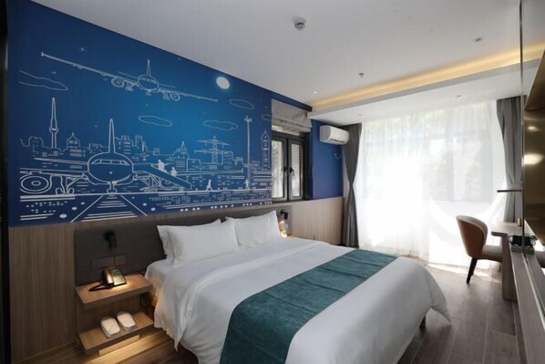 Una habitación de hotel moderna con una cama grande, un mural de paisaje urbano en la pared, un escritorio con silla y una ventana con cortinas.