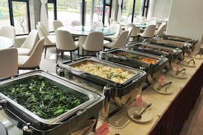 A buffet setup with various food options, including salads and hot dishes, in a dining area with chairs and tables. - Shanghai Hongzhu Garden Hotel (Shanghai)