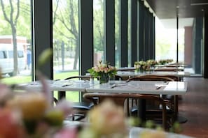 Un restaurante con mesas dispuestas para comer, amplios ventanales y vistas al exterior.