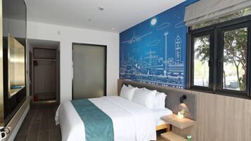 A modern hotel room with a large bed, a cityscape mural on the wall, a window with a view, and a small bedside table.