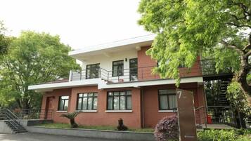 A two-story building with a flat roof, a balcony on the upper floor, and a staircase leading to the entrance.