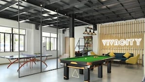 Une salle de billard équipée d’une table de billard, d’une table de ping-pong et d’un canapé.