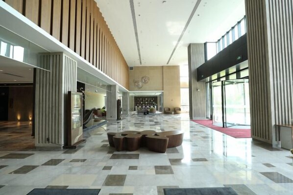 Un hall d’entrée spacieux avec un sol à carreaux, un coin salon et une cheminée.