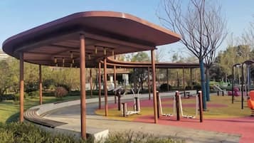 A park with a covered pavilion, exercise equipment, and a curved pathway.