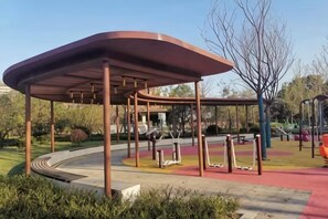 A park with a covered pavilion, exercise equipment, and a curved pathway.