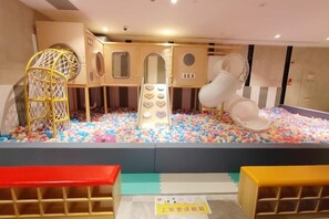 Een speelruimte voor kinderen met een bällebad, klimconstructies en zitplaatsen.