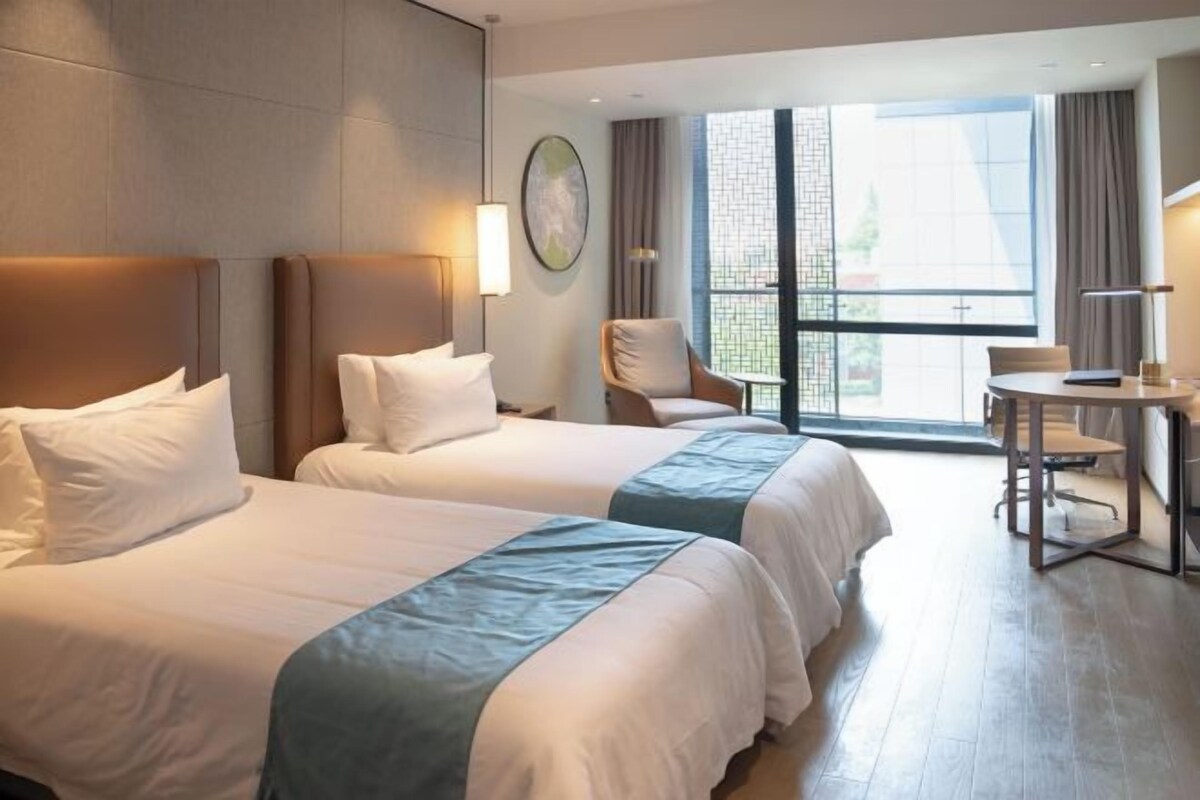 A hotel room with two beds, a desk, and a chair.