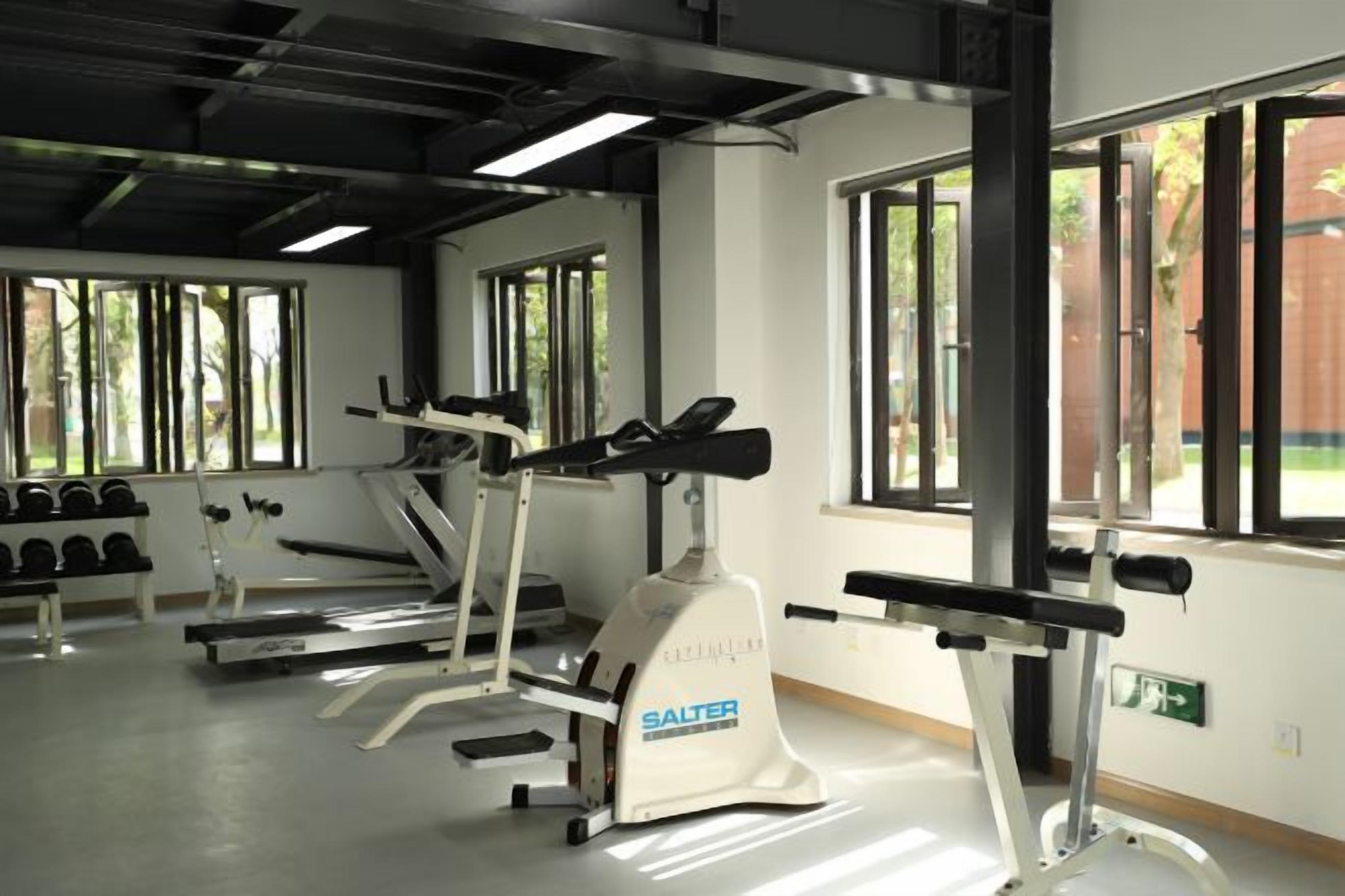 Un gimnasio con cintas de correr, mancuernas y máquinas de pesas.