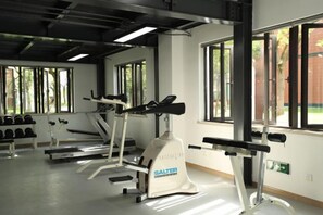 Une salle de sport équipée de tapis de course, d’haltères et d’appareils de musculation.
