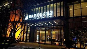 L’entrée d’un hôtel, avec une enseigne en caractères chinois et le texte en anglais : « SHUJI GARDEN HOTEL ».