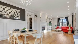 Un salon moderne avec un canapé rouge, un coin repas avec des chaises en bois et une cheminée.