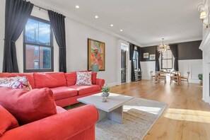 Uma sala de estar espaçosa com um sofá vermelho, uma mesa de centro e uma área de jantar com mobiliário de madeira.