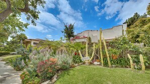 A residential property with a well-maintained garden, a paved driveway, and a white building with a red-tiled roof. - 2 Blocks to Melrose Ave! Home w/ Furnished Patio (Los Angeles)