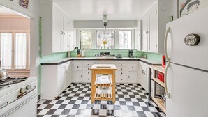 A kitchen with white cabinets, a checkered floor, a wooden stool, and a refrigerator with a Route 66 sign. - 2 Blocks to Melrose Ave! Home w/ Furnished Patio (Los Angeles)