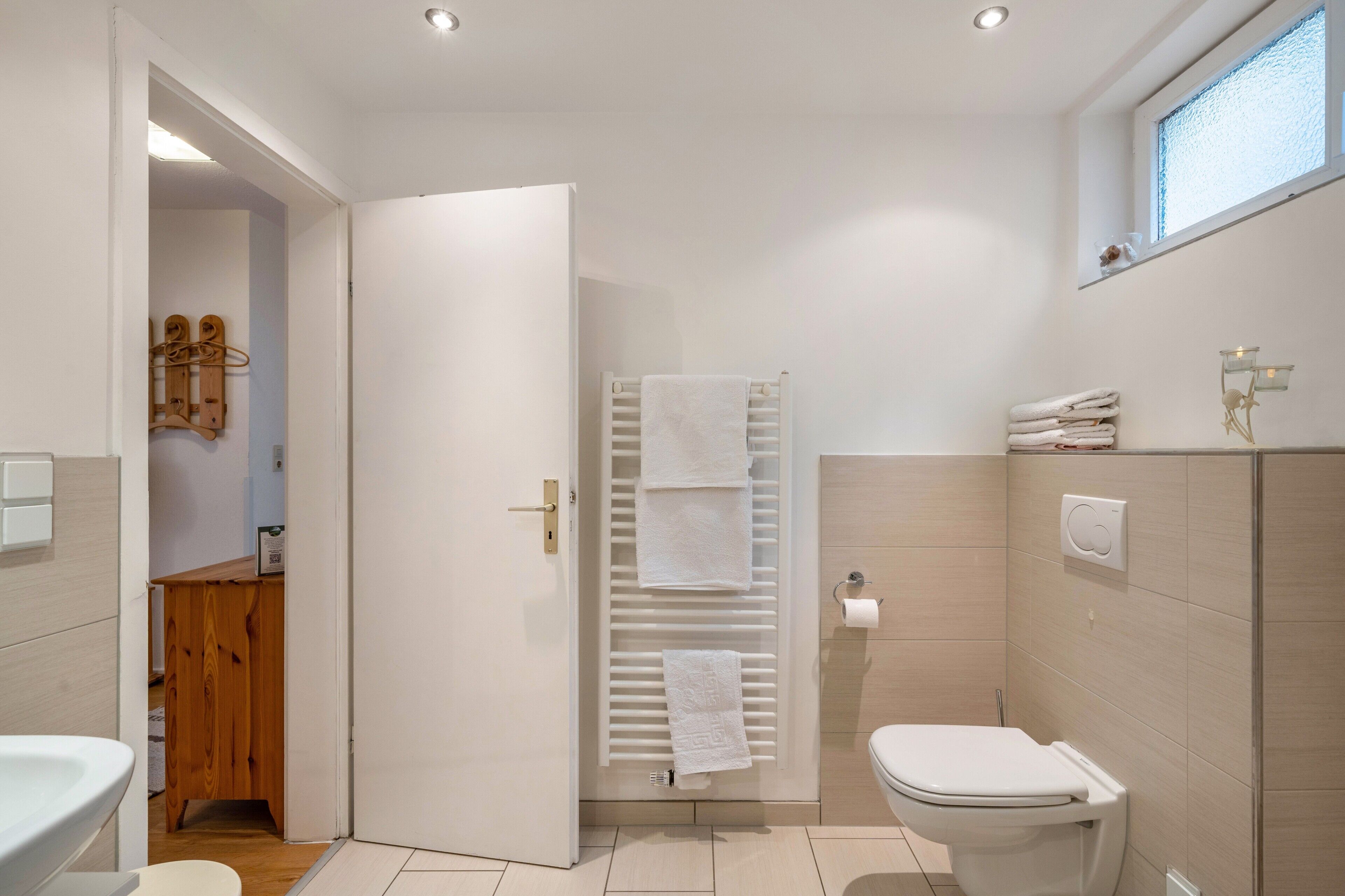 Ein modernes Badezimmer mit Toilette, Handtuchhalter und einem Holzschrank.