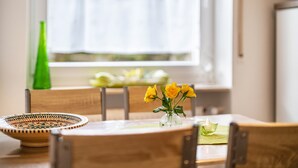 A dining table with a bowl, a vase with flowers, and a chair.