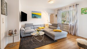 A living room with a grey sofa, a glass coffee table, and a painting on the wall.