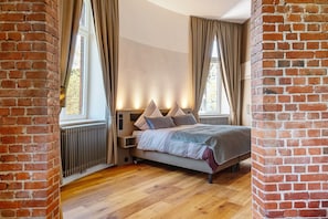 Une chambre avec un mur en briques, un lit avec des oreillers, un radiateur et une fenêtre.
