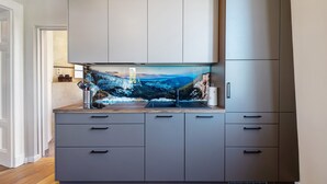 A modern kitchen with grey cabinets, a built-in island with a sink, and a large window displaying a scenic view. - Apartment 'Erstes Obergeschoss' with Wi-Fi (Cuxhaven)