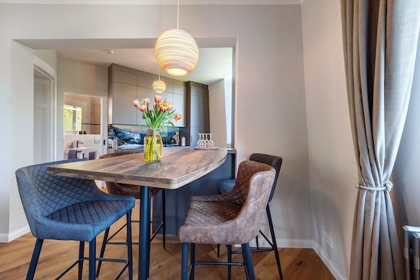 Une cuisine moderne dotée d’un îlot central, de luminaires suspendus et d’un vase rempli de fleurs.