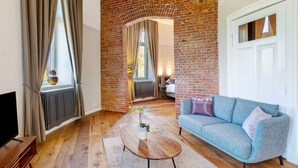 A living room with a brick wall, a sofa, a coffee table, and a TV. - Apartment 'Erstes Obergeschoss' with Wi-Fi (Cuxhaven)