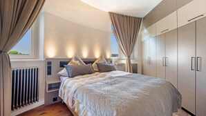 Un dormitorio con cama, mesitas de noche, un radiador y un armario.