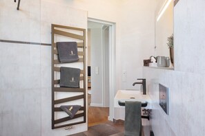 Ein modernes Badezimmer mit integriertem Handtuchhalter, einem Waschbecken und einem Spiegel.