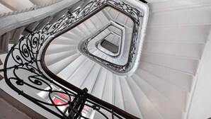 Una escalera de caracol con barandillas metálicas ornamentadas y un interior blanco.