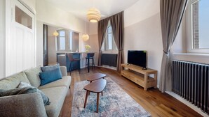 Una sala de estar moderna con sofá, mesa de centro, televisor y comedor.