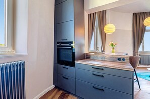 A modern kitchen with a built-in oven, a large mirror, and pendant lights.