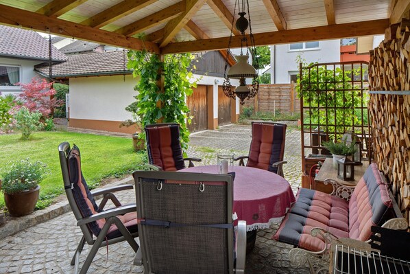 Une terrasse extérieure avec une table ronde, des chaises et un banc rembourré.