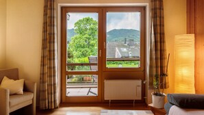 Une pièce avec un canapé, une table ornée de fleurs, un radiateur et une vue sur un paysage verdoyant par la fenêtre.
