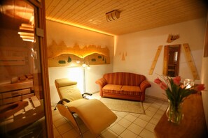 Una habitación con techo de madera, un sofá, una silla, un florero con flores y una pared con diseño de montaña.