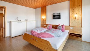 A wooden ceiling, a bed with a wooden frame, a white wardrobe, and a wall-mounted picture. - Apartment "Fichte" with Mountain View, Balcony, and Wi-Fi (Bernau im Schwarzwald)