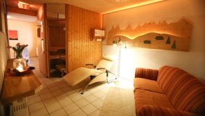 A cozy room with a wooden ceiling, a bed with a white headboard, a standing lamp, and a wall-mounted heater. - Apartment "Fichte" with Mountain View, Balcony, and Wi-Fi (Bernau im Schwarzwald)