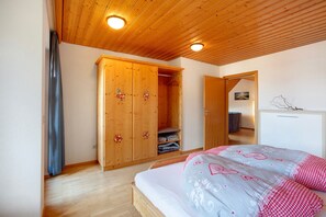 Un dormitorio con un armario de madera, una cama con ropa de cama estampada y un techo de madera.