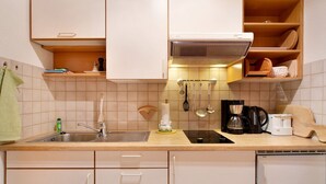 Een keuken met een spoelbak, aanrecht, kastjes en een koffiezetapparaat.