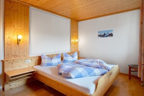 Un lit en bois avec une tête de lit, des tables de chevet et des lampes fixées au mur.