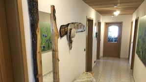 Un couloir orné de décorations murales en bois, avec un banc recouvert de fourrure et un sol carrelé à motifs hexagonaux.