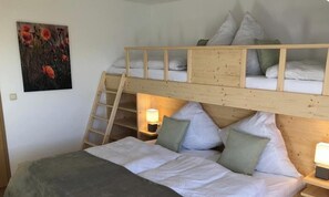 Une chambre avec un lit superposé, une échelle, des tables de chevet et un tableau accroché au mur.