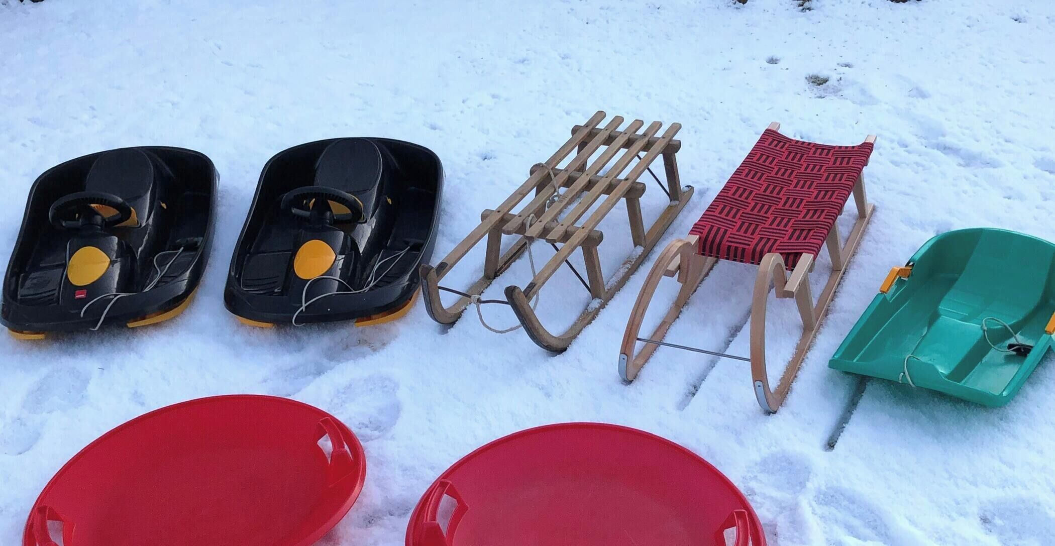 Des raquettes, une luge et deux luges rouges sur la neige.
