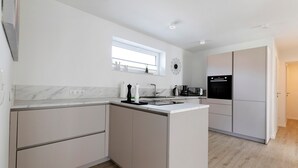 Una cocina moderna con encimera de mármol, armarios empotrados, un ventanal y un refrigerador negro.