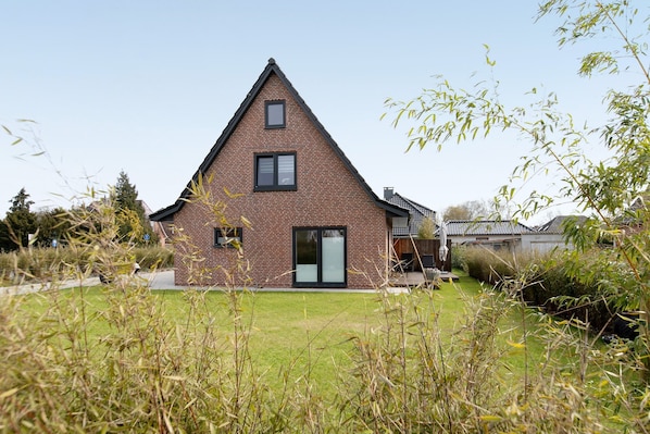 A single-story brick house with a triangular roof, a front door, and a small front yard.
