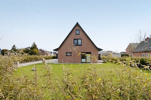 A single-story brick house with a triangular roof, a front door, and a small window on the upper floor.