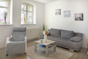 A living room with a grey sofa, a grey armchair, a coffee table, and a radiator.