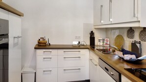 Una cocina con armarios blancos, encimera de madera, un lavamanos y un microondas.