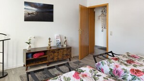 Un dormitorio con una cama, un armario de madera, un cuadro y una puerta que da a otra habitación.