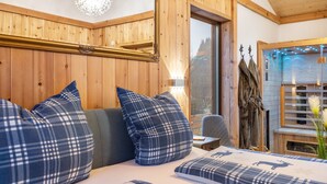 A wooden interior with a bed, pillows, a mirror, and a window.